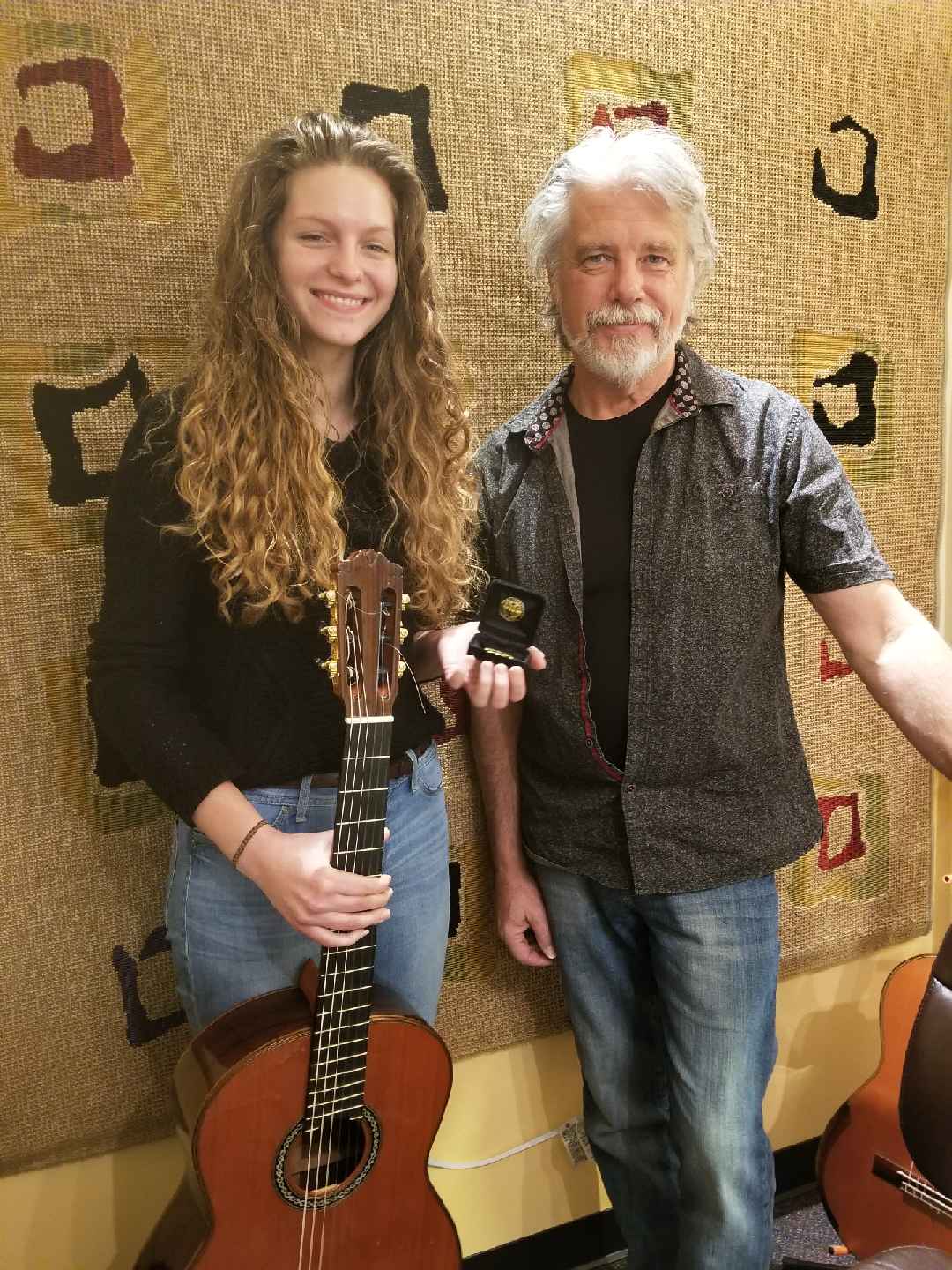 Larry McDonald with a student holding a guitar and medal
